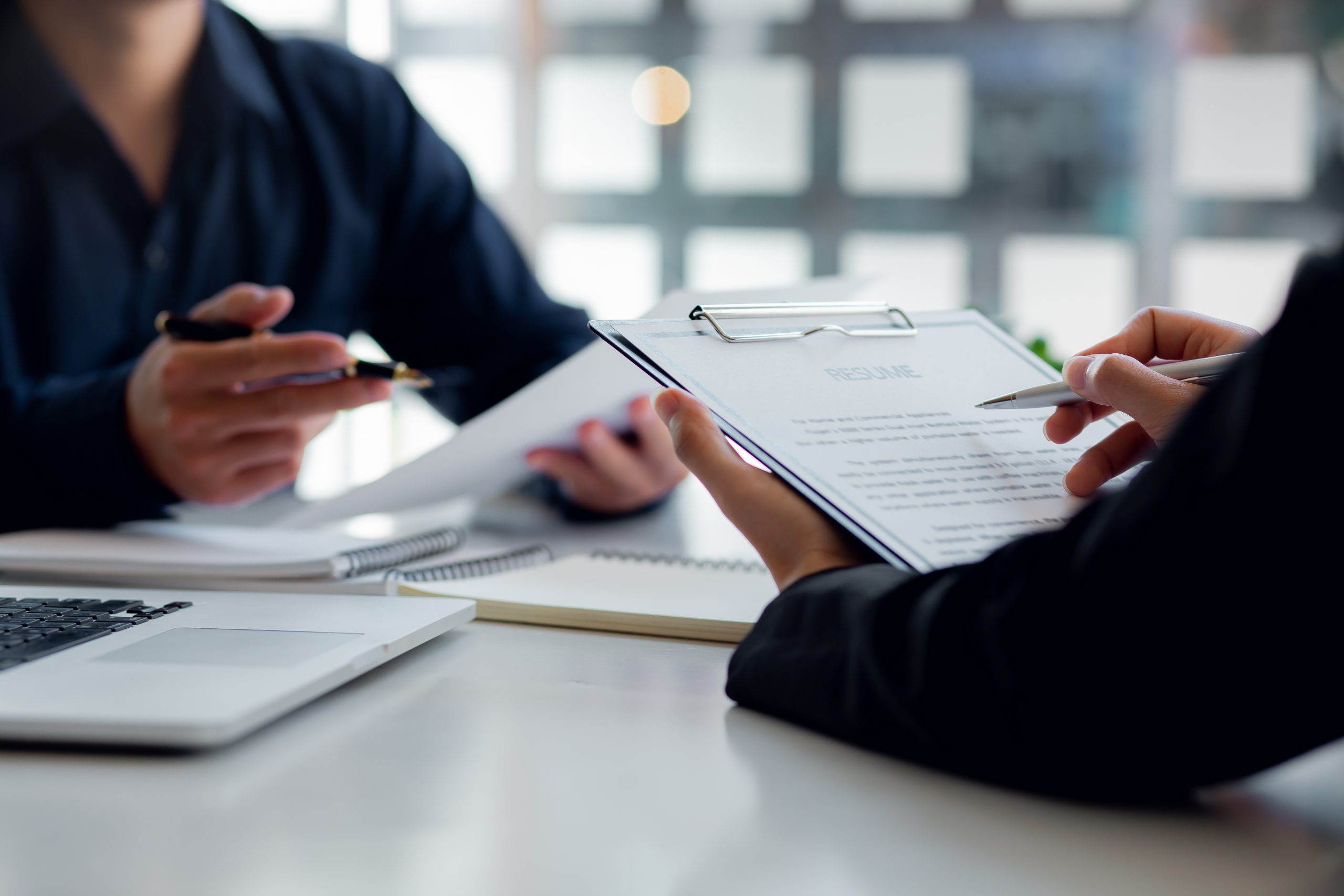 Male employer holding resume talking with female job candidate a